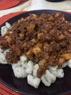 Una foto de Ñoquis de perejil con Bolognesa