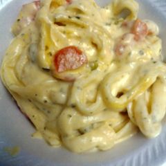 A picture of cheesy fettuccine with peas and carrots.