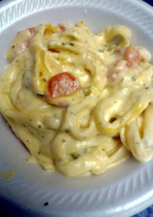 A picture of cheesy fettuccine with peas and carrots.