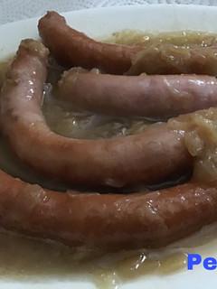 Una foto de Salchichas con cebolla caramelizada al vino blanco envejecido