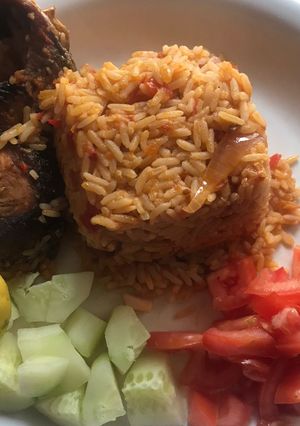 A picture of Fish, jollof rice and veggies.