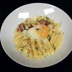 A picture of Penne' Pasta with back bacon white sauce and poached egg.