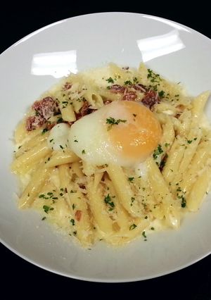A picture of Penne' Pasta with back bacon white sauce and poached egg.