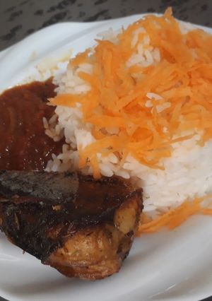A picture of Boiled rice with sauce and fried titus fish.