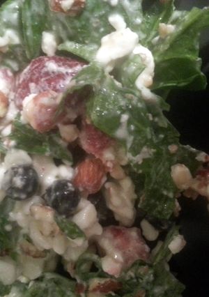 A picture of spinich, berry, nuts, and cheese salad..