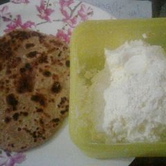 A picture of Aloo pratha with white butter.