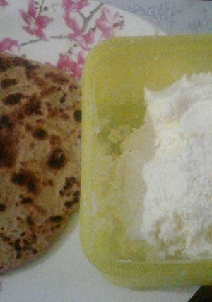 A picture of Aloo pratha with white butter.
