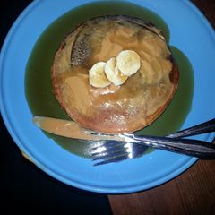 A picture of pancakes with banana and peanut butter.