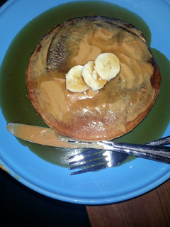 A picture of pancakes with banana and peanut butter.