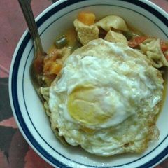 A picture of Tofu and mushroom soupy mixed pasta served with fried eggs..
