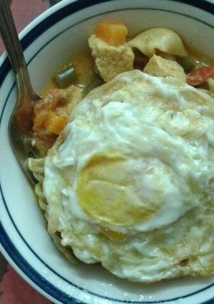A picture of Tofu and mushroom soupy mixed pasta served with fried eggs..