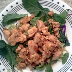 A picture of Roasted chicken in marinated sundried tomatoes atop kale salad.