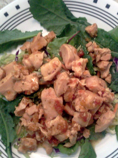 A picture of Roasted chicken in marinated sundried tomatoes atop kale salad.