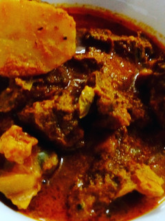 A picture of Bengali goat meat curry with potato.
