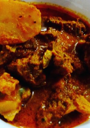 A picture of Bengali goat meat curry with potato.