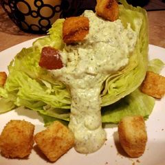 A picture of Herbed green goddess dressing over lettuce wedges.