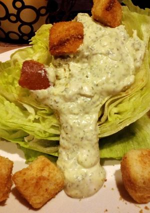 A picture of Herbed green goddess dressing over lettuce wedges.