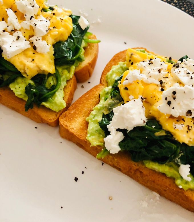 A picture of Avo toast with spinach, scrambled eggs and feta.