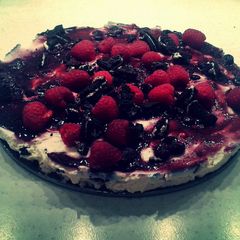 A picture of Oreo Cheesecake With Raspberries & Blueberry Syrup.