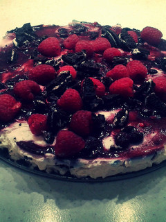 A picture of Oreo Cheesecake With Raspberries & Blueberry Syrup.