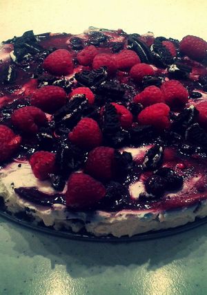 A picture of Oreo Cheesecake With Raspberries & Blueberry Syrup.