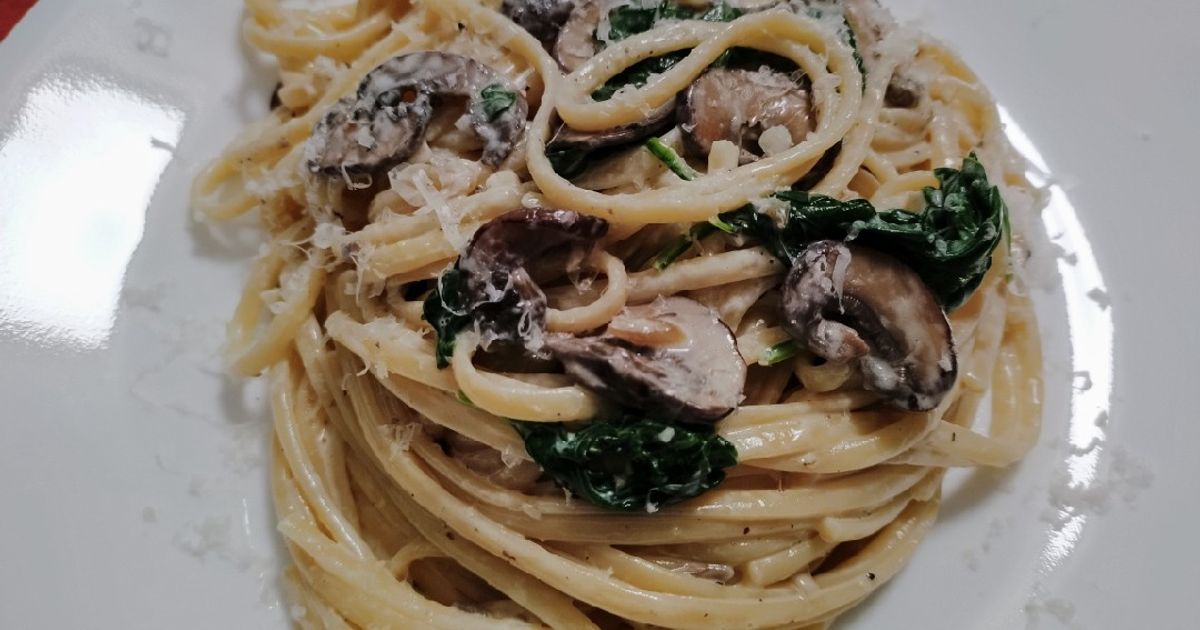 A top-down view of a delicious plate of pasta with a smooth, white cream sauce and herbs