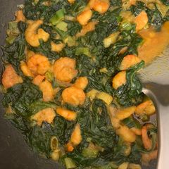 A picture of King prawns curry with spinach.