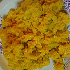 A picture of Scramble eggs with leftover yellow rice and chicken.
