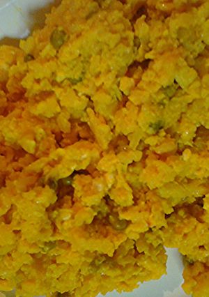 A picture of Scramble eggs with leftover yellow rice and chicken.