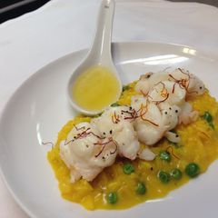 A picture of Lobster poached in vanilla bean butter served with saffron, sweet pea risotto.