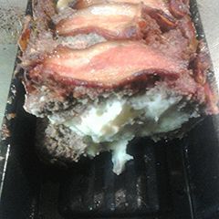A picture of Bacon wrapped meatloaf, stuffed with garlicky mashed potatoes.