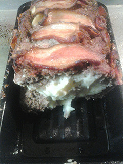 A picture of Bacon wrapped meatloaf, stuffed with garlicky mashed potatoes.