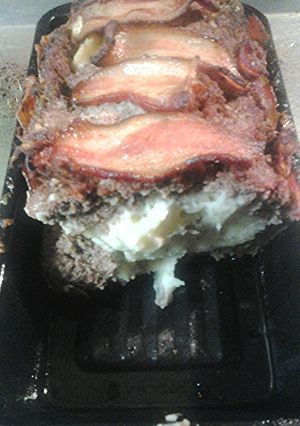 A picture of Bacon wrapped meatloaf, stuffed with garlicky mashed potatoes.