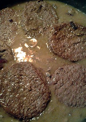 A picture of onions mushrooms and sirloin burgers in gravy.