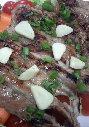 A picture of Moo Kam Waan / Thai style Grilled Pork serve with Spicy Sauce and fresh vegetables.