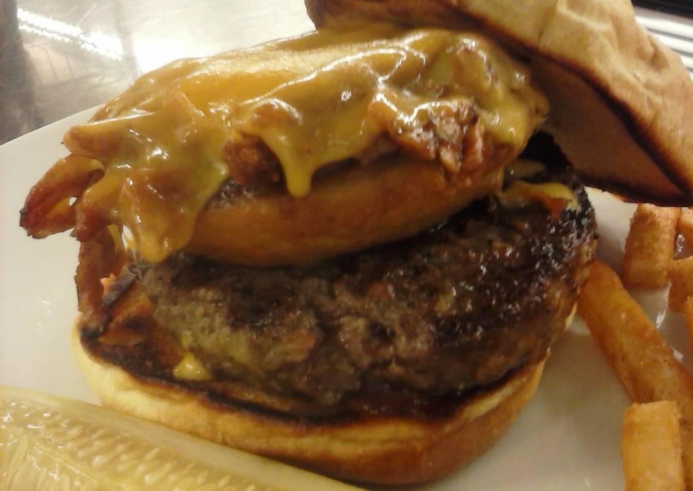 Beef Tender loin burger with pulled pork stuffed onion ring and melted cheddar cheese
