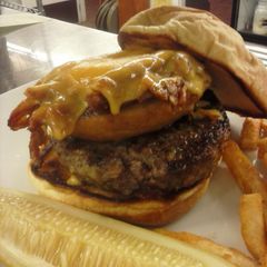 A picture of Beef Tender loin burger with pulled pork stuffed onion ring and melted cheddar cheese.