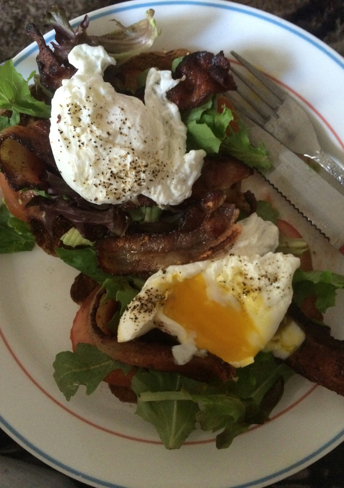 A picture of Avocado toast with poached eggs & bacon.