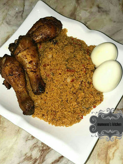 A picture of Jallof cous cous wt grilled chicken drumsticks n boiled eggs.
