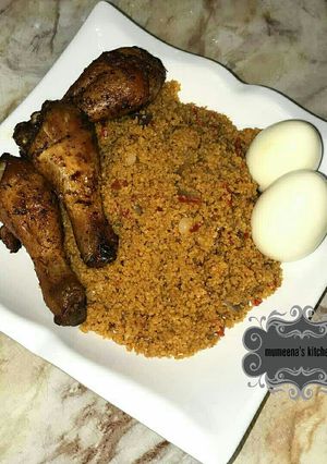 A picture of Jallof cous cous wt grilled chicken drumsticks n boiled eggs.