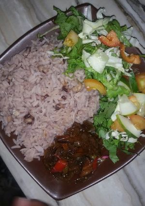 A picture of Boiled rice and beans with onion sauce and salad.