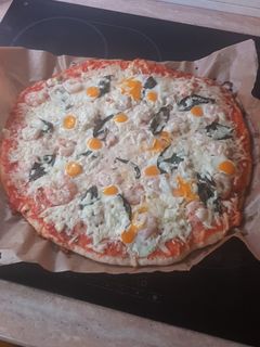 Una foto de Pizza de gambas, ajetes y albahaca