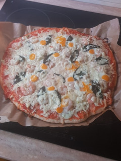 Una foto de Pizza de gambas, ajetes y albahaca