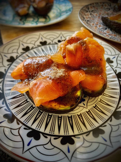 Una foto de Aguacate a la parrilla con burrata, salmón marinado y salsa de trufa con miel