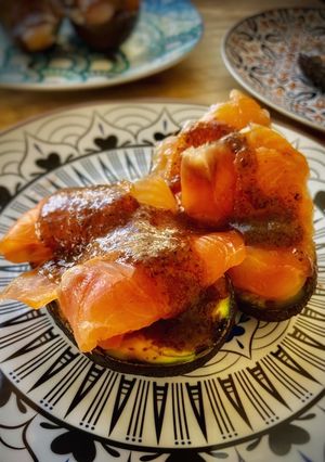 Una foto de Aguacate a la parrilla con burrata, salmón marinado y salsa de trufa con miel