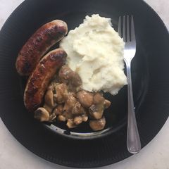 A picture of Pork bangers with creamy mashed potatoes and mushroom sauce.