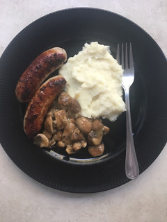 A picture of Pork bangers with creamy mashed potatoes and mushroom sauce.