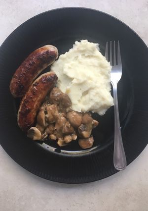 A picture of Pork bangers with creamy mashed potatoes and mushroom sauce.