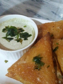 A picture of Homemade veg samosas with hari chutney.