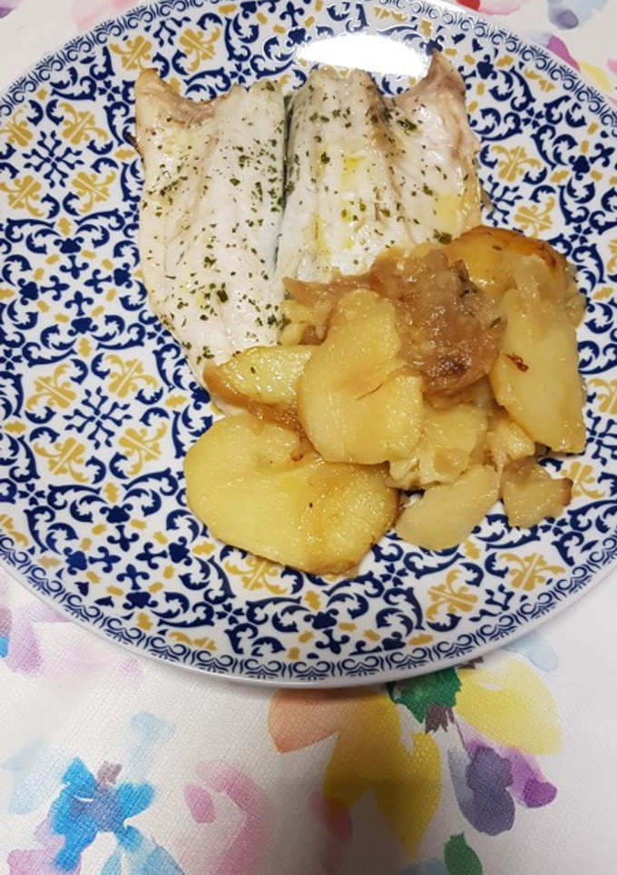 Una foto de Lubina al horno con patatas y cebolla